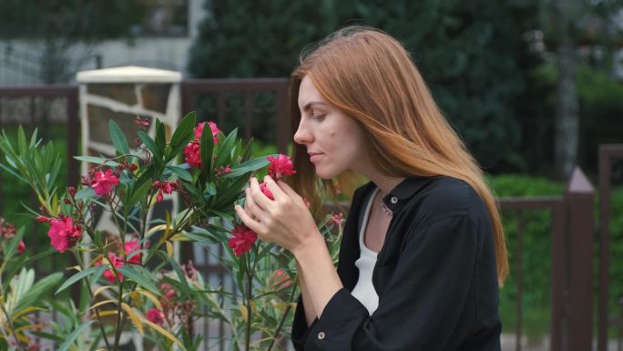 一个美丽的年轻女子在她家附近的花园里欣赏美丽的花朵