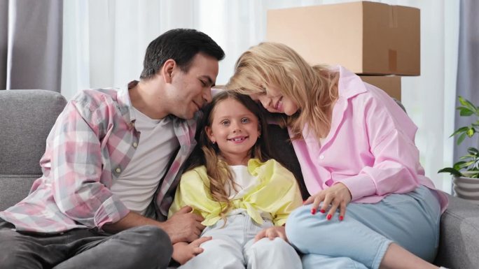 家庭爱情画像。父母和小女儿坐在沙发上。看镜头。