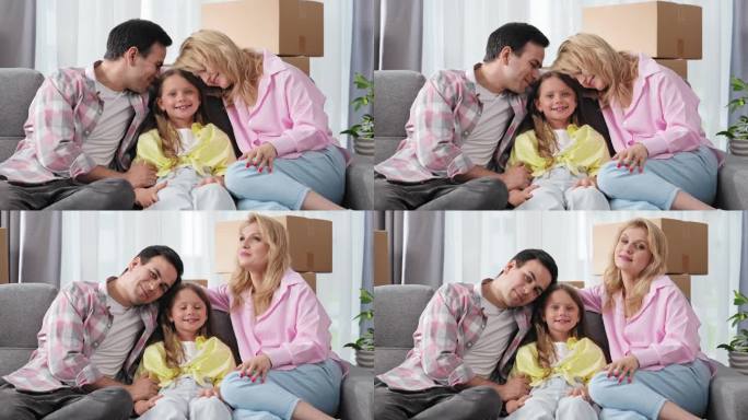 家庭爱情画像。父母和小女儿坐在沙发上。看镜头。