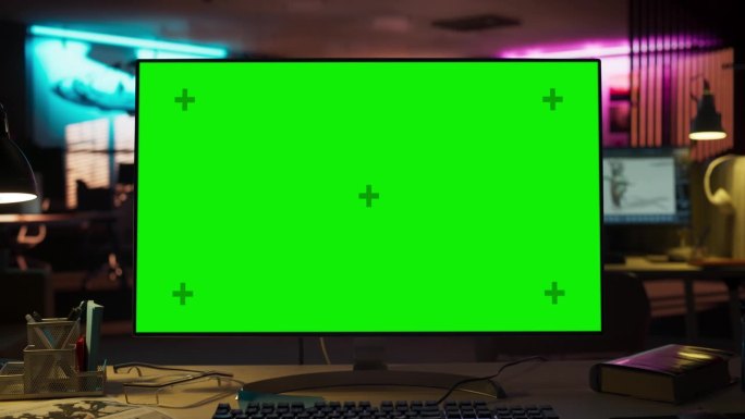 缩小镜头的桌面电脑显示器与绿色屏幕Chromakey模拟显示器的木桌。创意机构游戏开发者办公室工作站