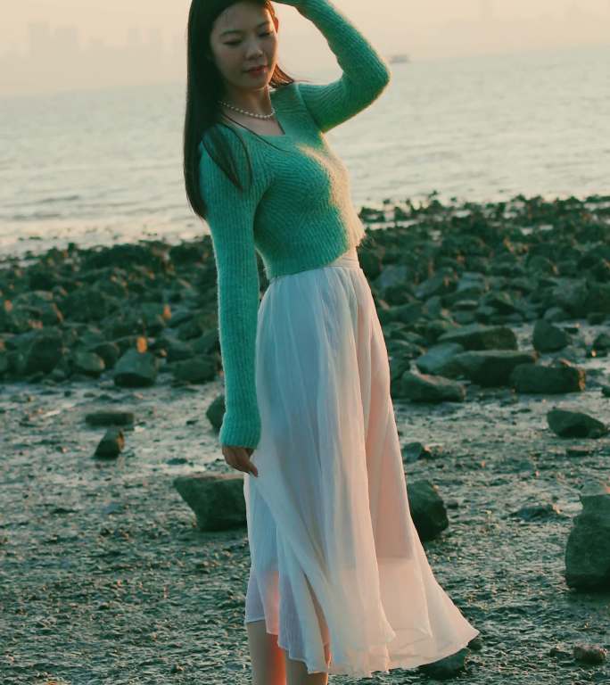 漂亮女人身着白裙在海滩迎接第一缕阳光升起