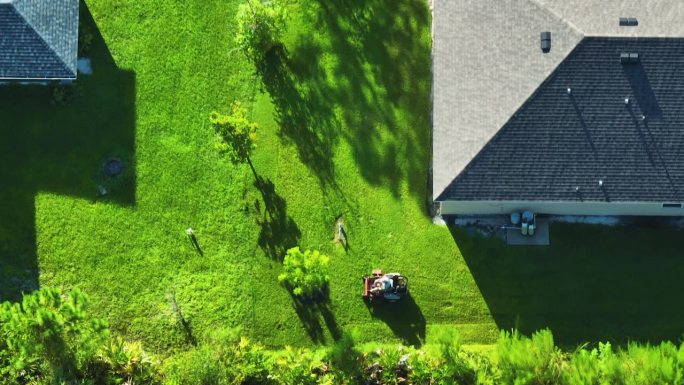 夏季，草坪修剪专业服务人员正在用割草机割草。农村家庭后院景观美化