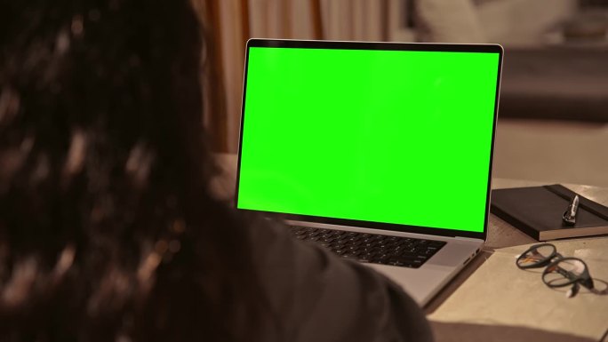 女人在笔记本电脑上工作或看绿屏模拟色度键和视频通话。远程办公或在网上聊天的人讨论特写。观看视频通话或