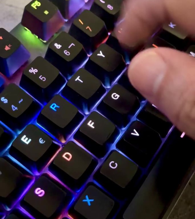 手按游戏电脑键盘的特写，背光黑键变色，人的手敲击键盘，RGB光，4k，垂直