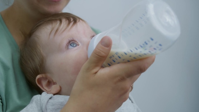 一名妇女在明亮的病房里用奶瓶喂孩子的特写