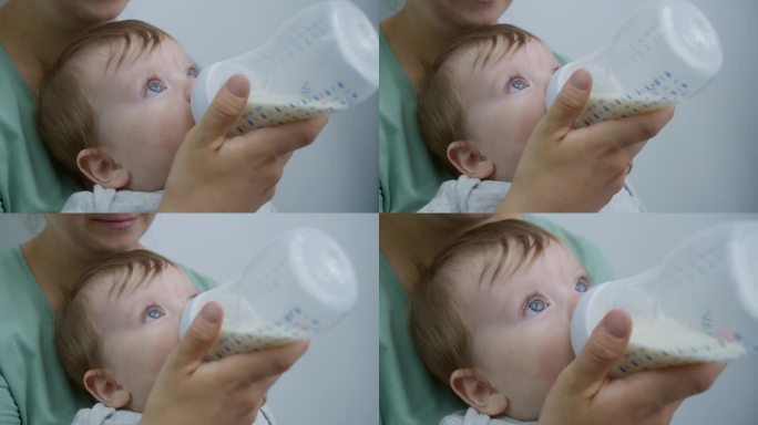 一名妇女在明亮的病房里用奶瓶喂孩子的特写