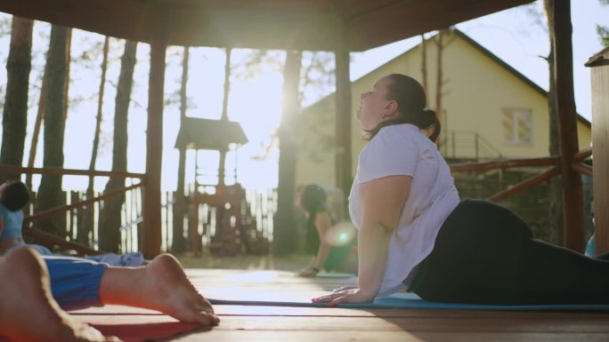 超重妇女在减肥营做体育锻炼，练习瑜伽，健康的生活方式