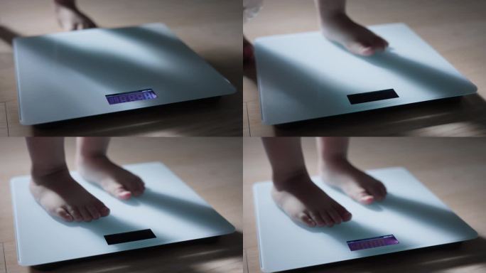 小婴儿赤脚站在家里的木地板上称体重。儿童体重控制概念。