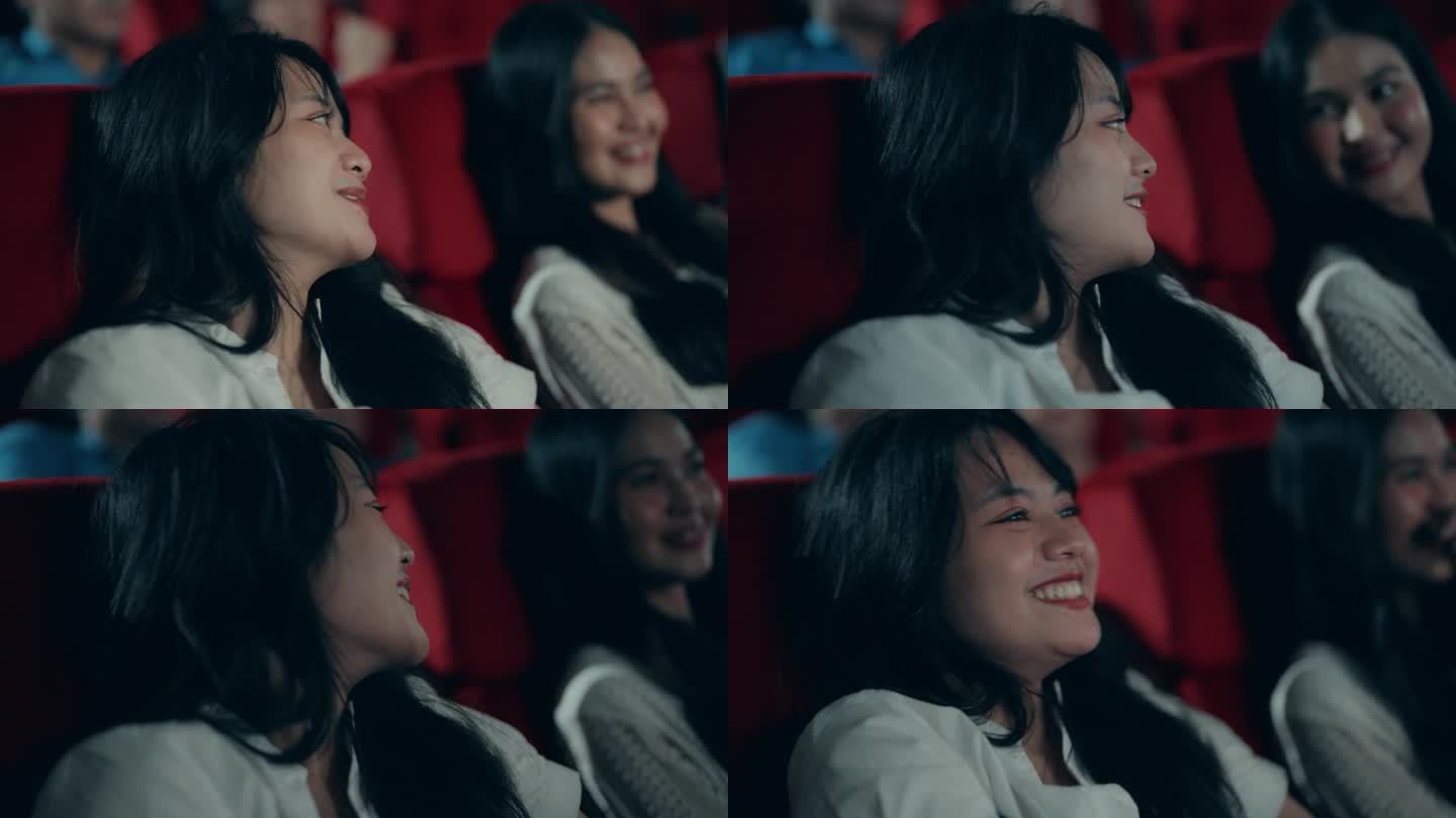 微笑的亚洲女人在电影院欣赏电影。