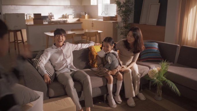 一个幸福的韩国家庭来到他们新买的房子:父母和他们可爱的孩子为新的开始而兴奋，一起分享他们生活中的一个