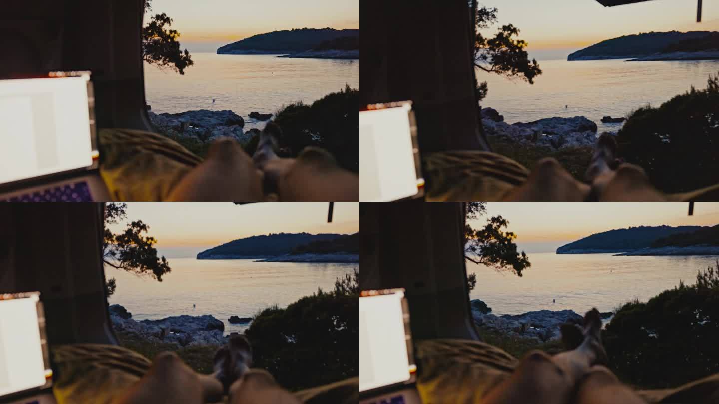 日落时分，一个人躺在露营车的床上，手提电脑旁