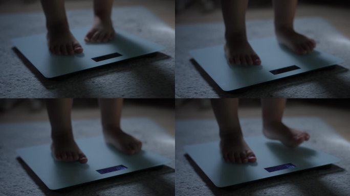 小婴儿赤脚站在家里地毯地板上的体重秤上。儿童体重控制概念。