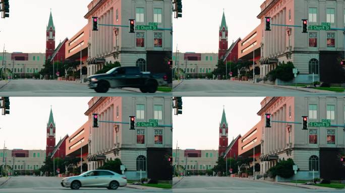 美国伊利诺斯州罗克福德教堂街400号。以教堂为背景拍摄的日落。交通灯显示红色。黑色汽车驾驶。
