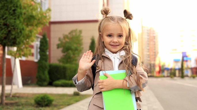 回到学校，一个一年级的女孩挥手告别她的父母，一个女学生带着背包或公文包上学，一个快乐的孩子在学校附近