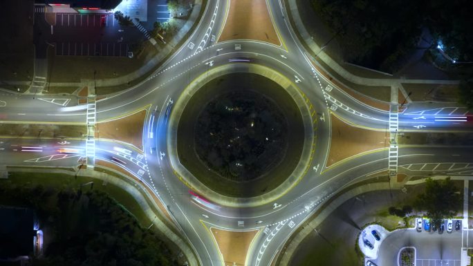 城市街道交通的俯视图在夜间环岛交叉路口快速移动的汽车。照明城市环形交通十字路口的时间间隔