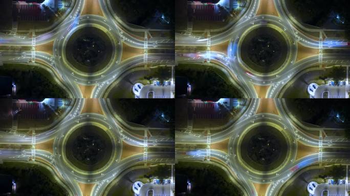 城市街道交通的俯视图在夜间环岛交叉路口快速移动的汽车。照明城市环形交通十字路口的时间间隔