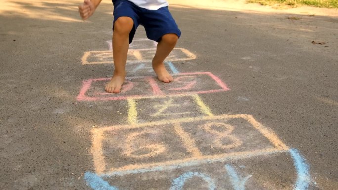 孩子们在外面玩跳房子游戏。有选择性的重点。夏天。