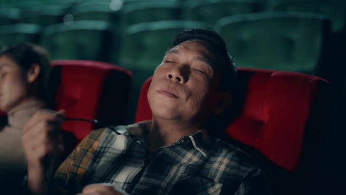 亚洲男人寻找宁静:在舒适的电影院入睡。