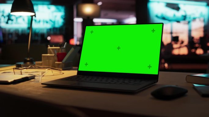 放大笔记本电脑绿屏模型站在木桌上。在背景时尚的现代办公室工作室在霓虹灯的晚上。创意设计师办公桌
