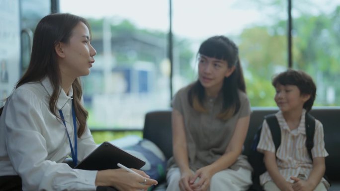 一位亚洲母亲和孩子兴致勃勃地与老师谈论在国际学校学习英语的事情。