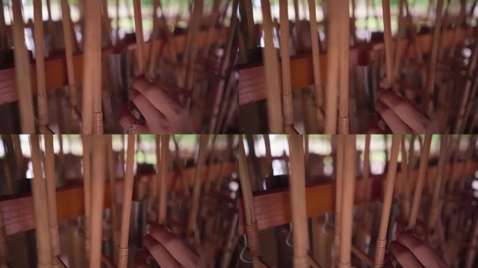 女性手持angklung的特写，angklung是一种来自爪哇的传统印尼乐器，由竹子制成。通过摇动来