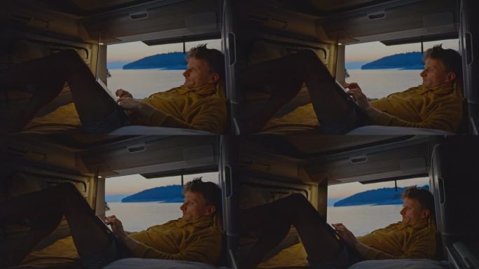 一名男子斜倚在露营车的床上使用笔记本电脑