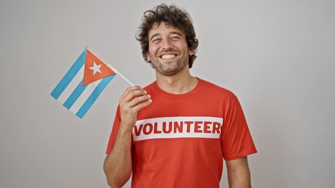 年轻的西班牙裔男子在孤立的白色背景上举着古巴国旗