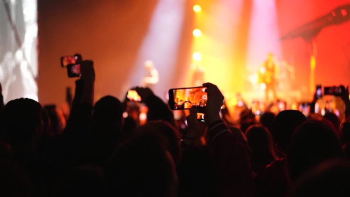 开心的歌迷用手机拍演唱会。人们在聚会上录制视频