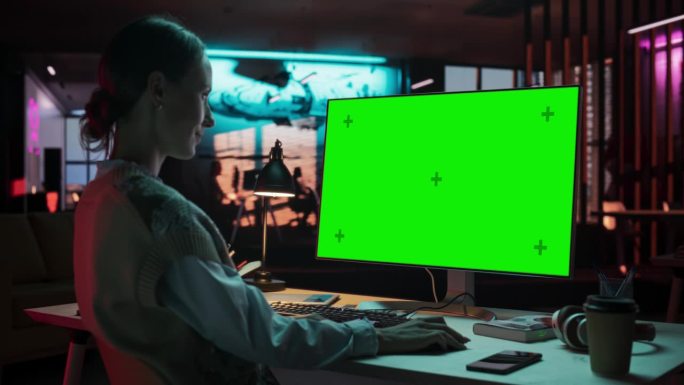 在肩膀上:年轻女子坐在她的办公桌前使用桌面电脑与模拟绿屏。女性高加索专家工作与彩色键显示在创意机构的