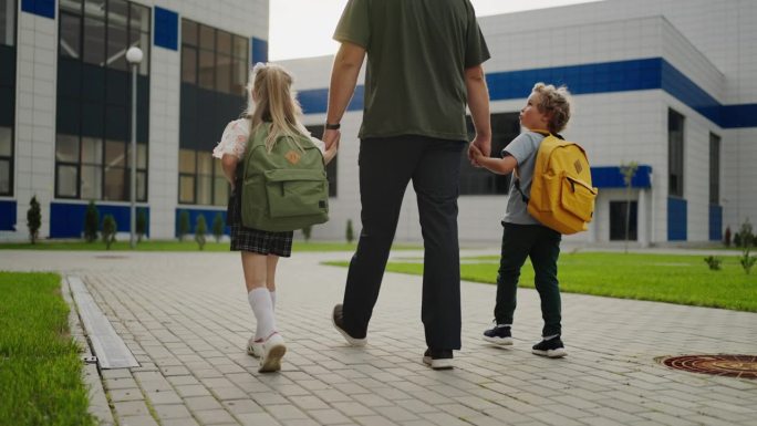 孩子上学，孩子牵着爸爸的手走在操场上，后视图，学生