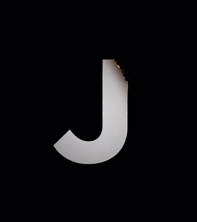 火字母显示和消失动画。J符号燃烧像纸烬和烟在黑色的背景。设计元素