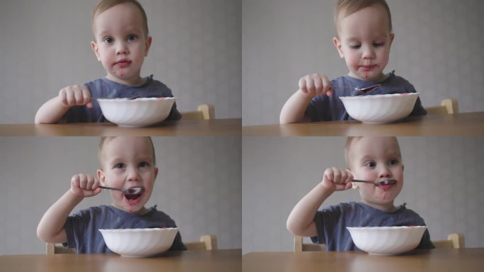 小婴儿蹒跚学步的孩子用手里的勺子喝汤，学习自己喂食