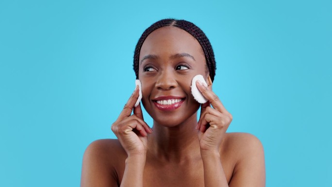 非洲妇女，化妆棉和护肤用品在演播室，清洁面部或满意的结果，蓝色的背景。女孩，模特或微笑与美丽，发光或