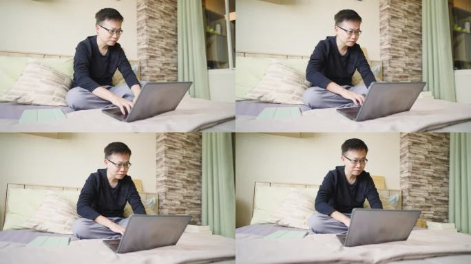 年轻人坐在床上，在家里的卧室里用笔记本电脑工作