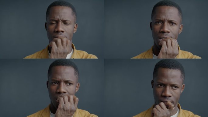 紧张的非裔美国人咬指甲，看着镜头的特写慢动作肖像