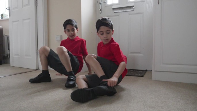 两个小男孩在家的走廊上穿校服