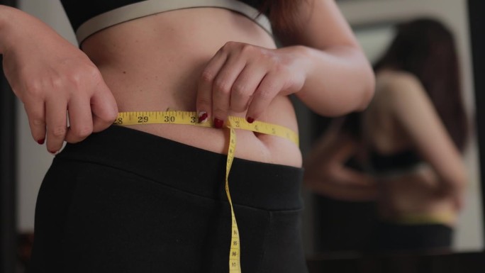 超重的女人用卷尺测量她的胖肚子，超重的胖肚子的女人，胖女人，胖女孩，女人减肥的生活方式概念。