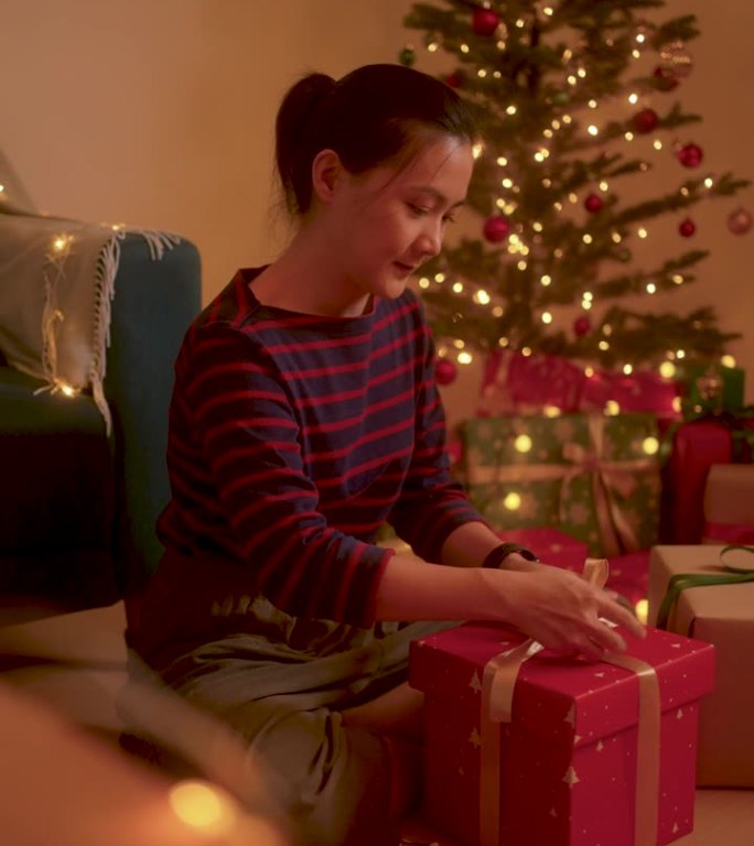 亚洲女人开心地微笑着包装圣诞礼盒。
