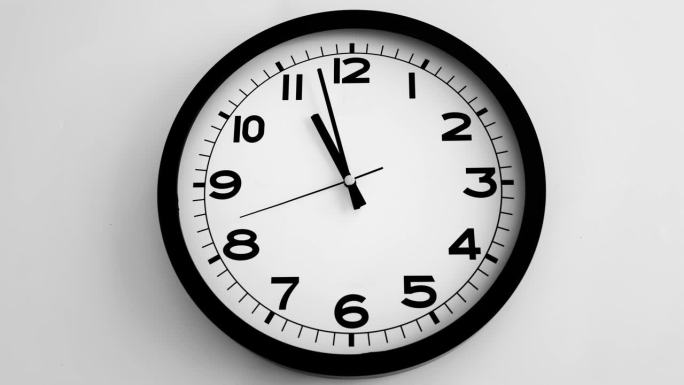 白色挂钟上的白色钟面特写，箭头显示23.00或11.00