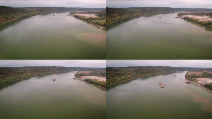 美国多云的一天，驳船上的无人机镜头在俄亥俄河的海岸线上与沙矿一起旅行