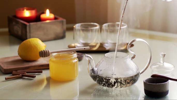 将热气腾腾的水倒入煮绿茶的透明壶中。