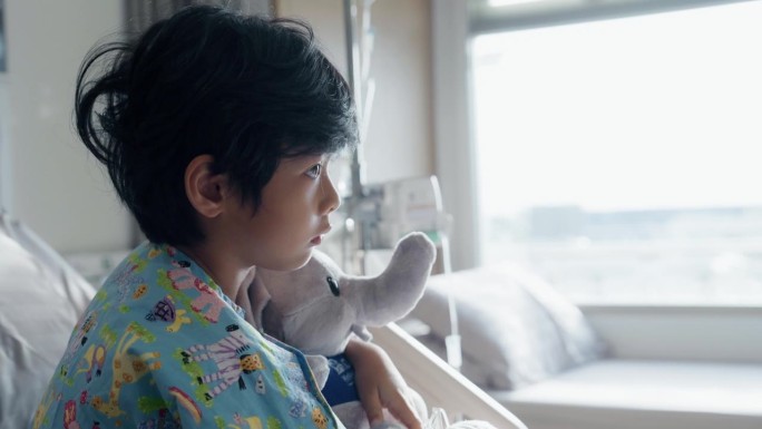 一个小病人带着一个可爱的洋娃娃躺在医院的病床上，头痛不已。