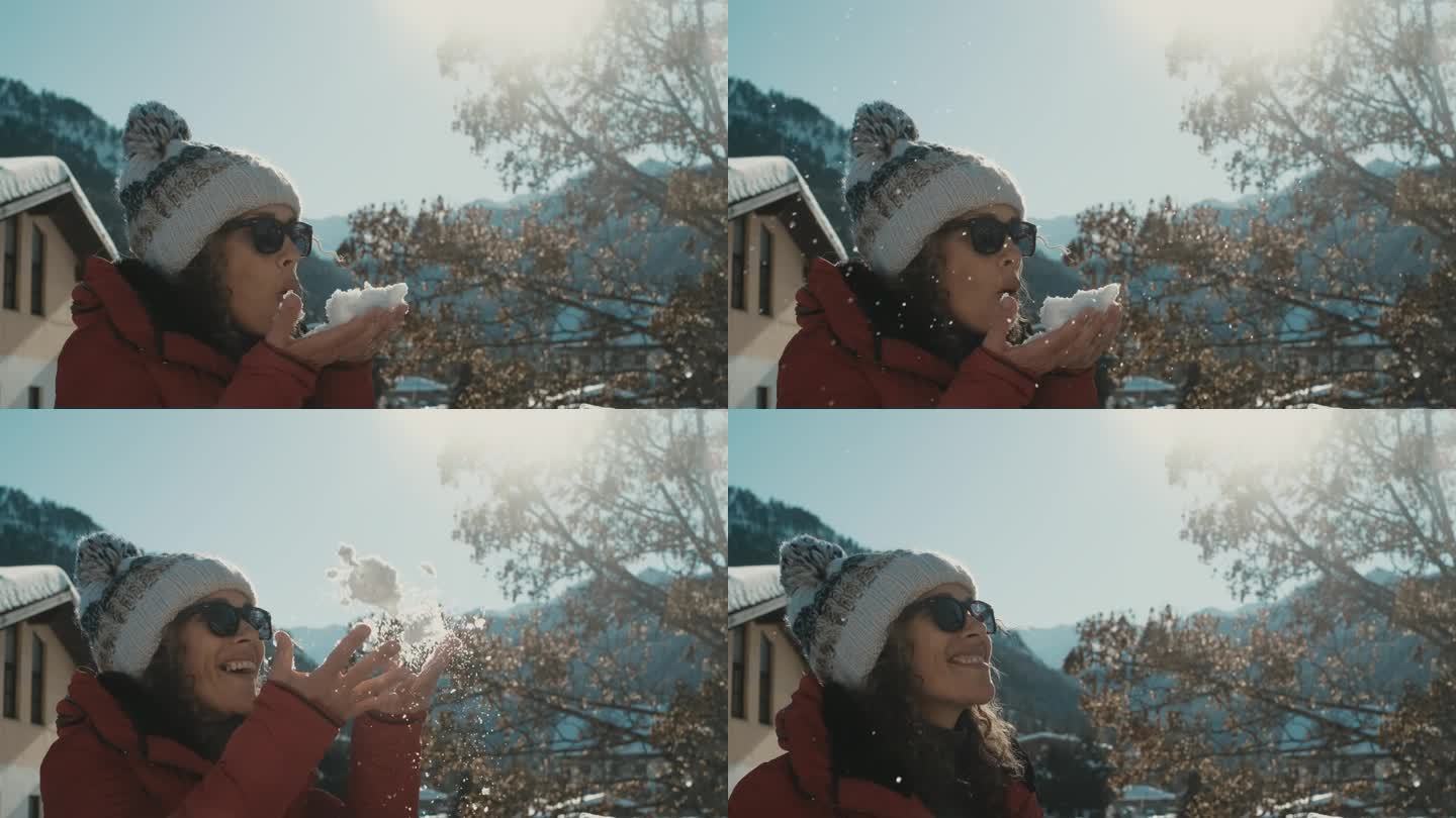 一个女人吹着软绵绵的雪，独自在寒假的户外快乐休闲。快乐的游客享受山地旅游季节。女人们快乐自由的生活理