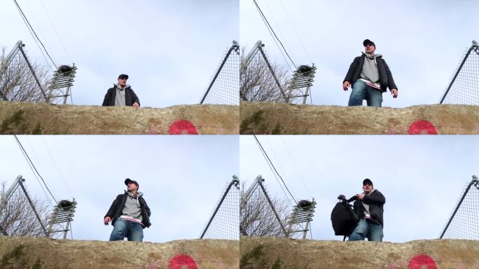 低角度拍摄的白人男摄影师站在一块石头地上卸下背包的画面