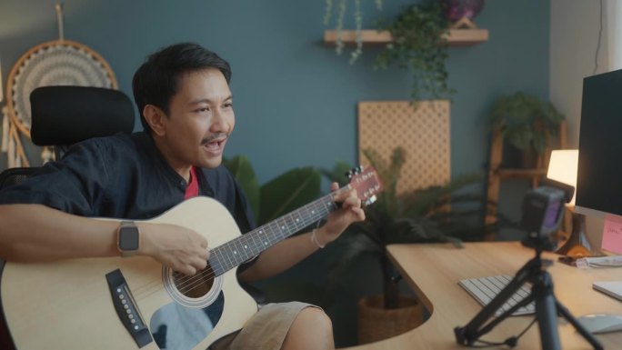 快乐的亚洲人教吉他在线学生在家庭工作室周末。