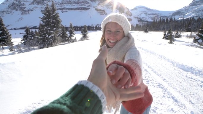 跟我来概念:一对夫妇手牵着手，女人带着男人走向雪景