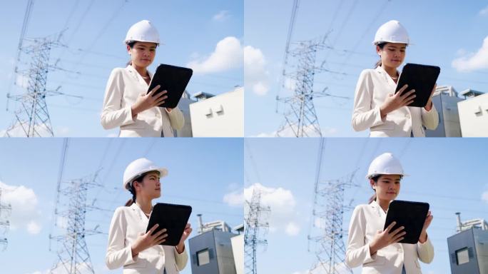 一位戴着防护头盔、身穿白色工作服的女电气工程师在一家电厂的工作现场。