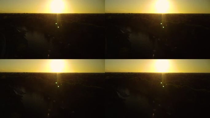 太阳光线照在相机上，俯视图，无人机在日落时飞过森林和河流