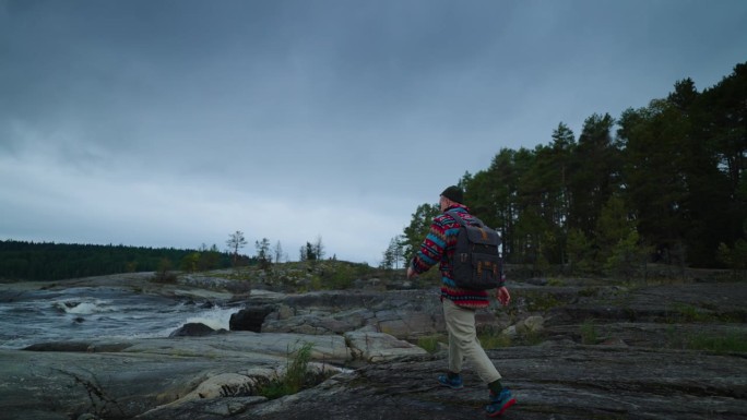 快乐男子游客与背包独自走在美丽的湖岸，后视图，以下镜头