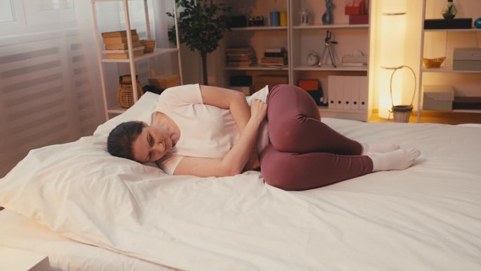 悲伤的女人躺在床上时痛经，子宫内膜异位症的问题